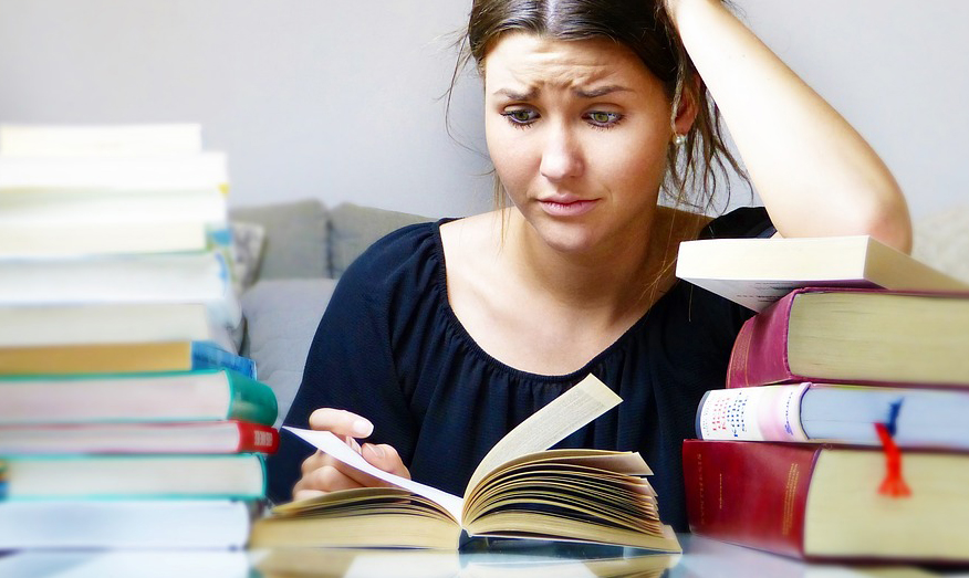Woman surrounded by books, she looks overwhelmed